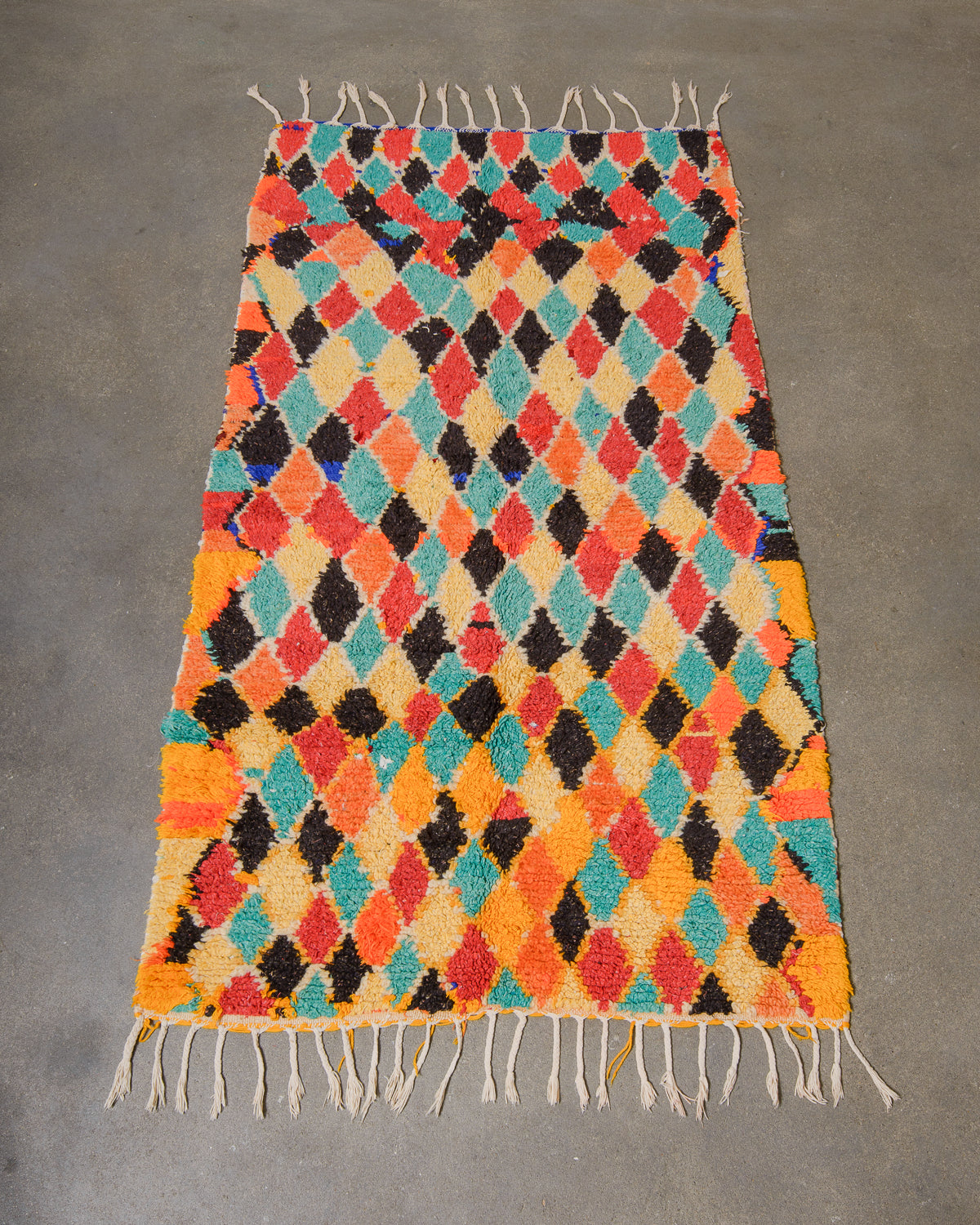 Multicolored woven rug with diamond pattern on a gray background